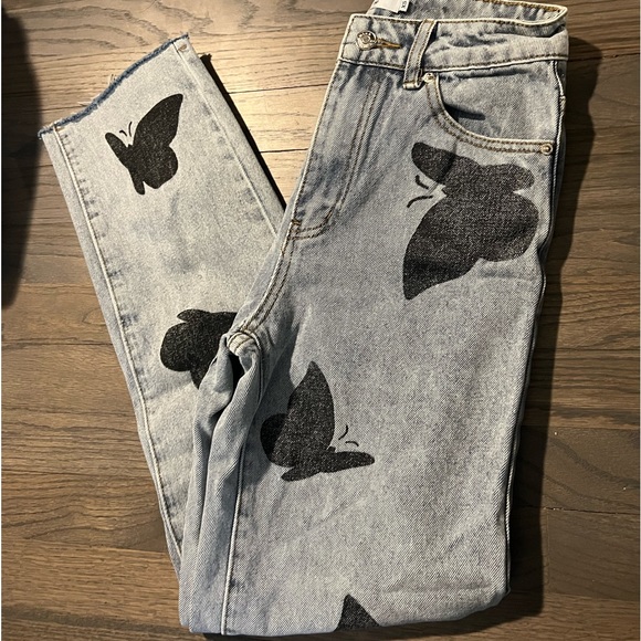 Medium wash straight leg jeans with butterfly details and distressed bottom. - Picture 1 of 3